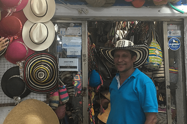A man standing in front of a store with many hats on the wall.