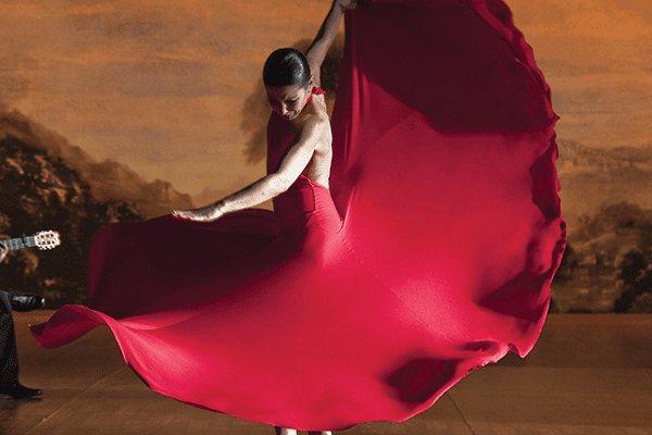 A woman in red dress dancing on the floor.
