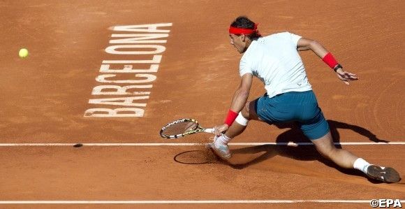 A man kneeling down on the ground holding a tennis racket.