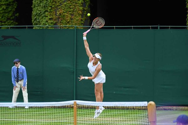A woman swinging at a tennis ball with her racket.