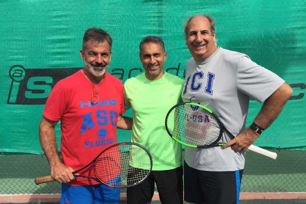 Three men holding tennis rackets on a court.