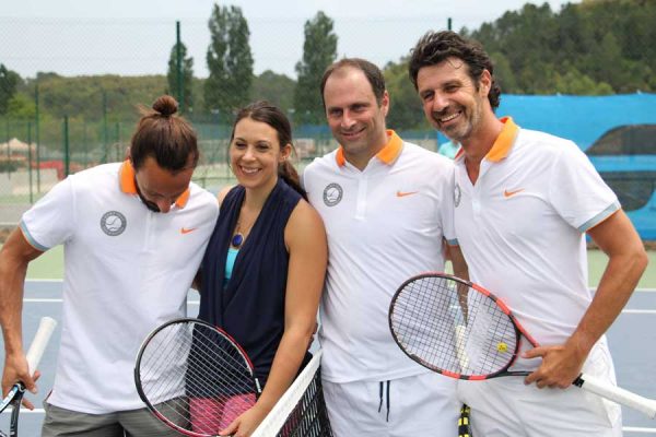 A group of people holding tennis rackets on top of a court.