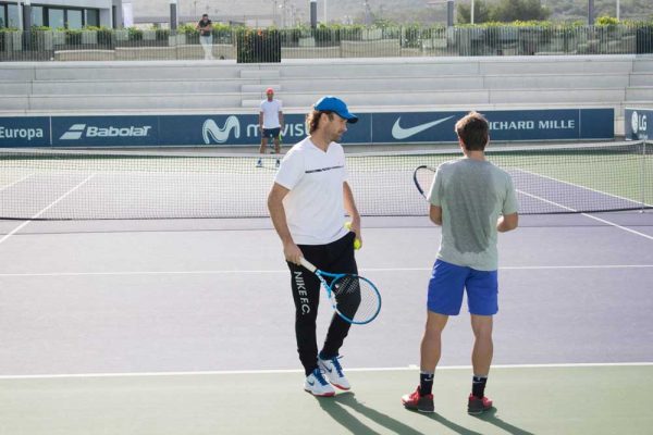 Two men are standing on a tennis court holding rackets.