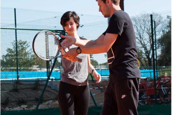 A man and woman holding tennis rackets on a court.