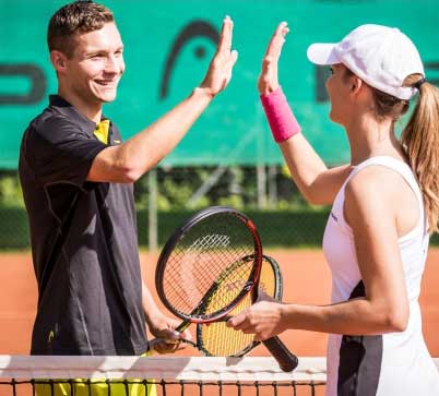 Two people giving each other a high five on the tennis court.