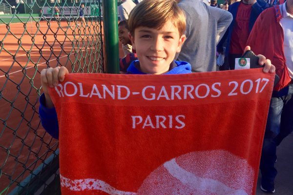 A young boy holding up a towel with the name of paris on it.