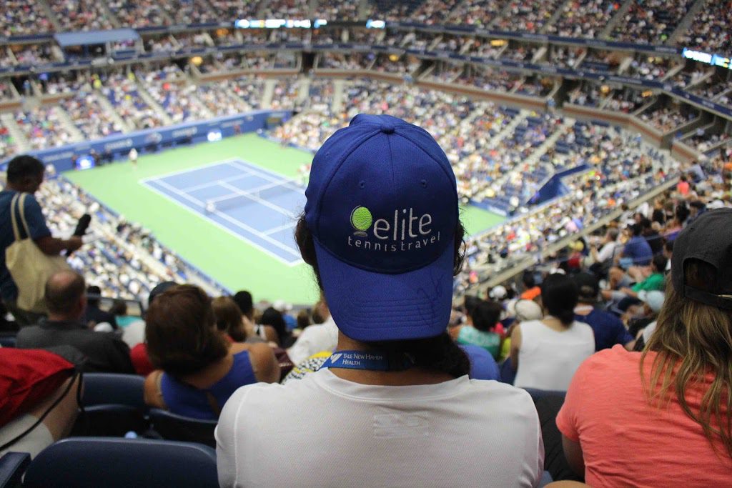 A person wearing a hat is sitting in the stands of a tennis match.