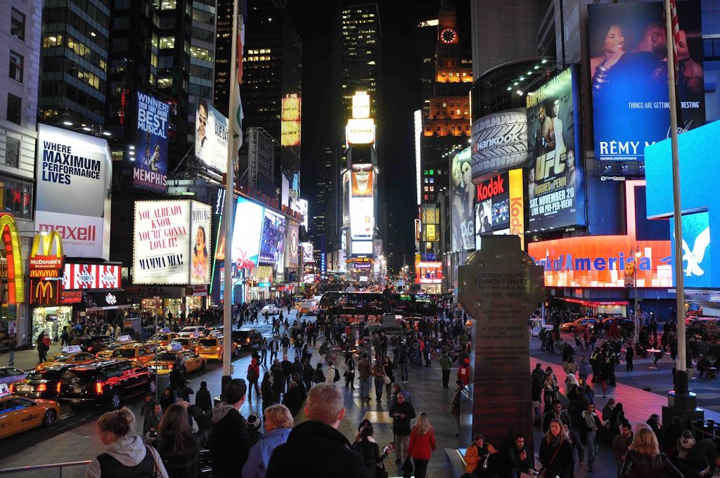 A crowd of people walking down the street in a city.