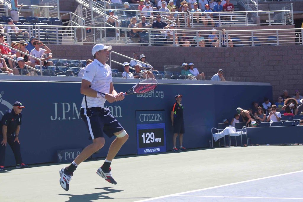 A man swinging a tennis racket on top of a court.