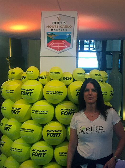 A woman standing in front of a large pile of tennis balls.