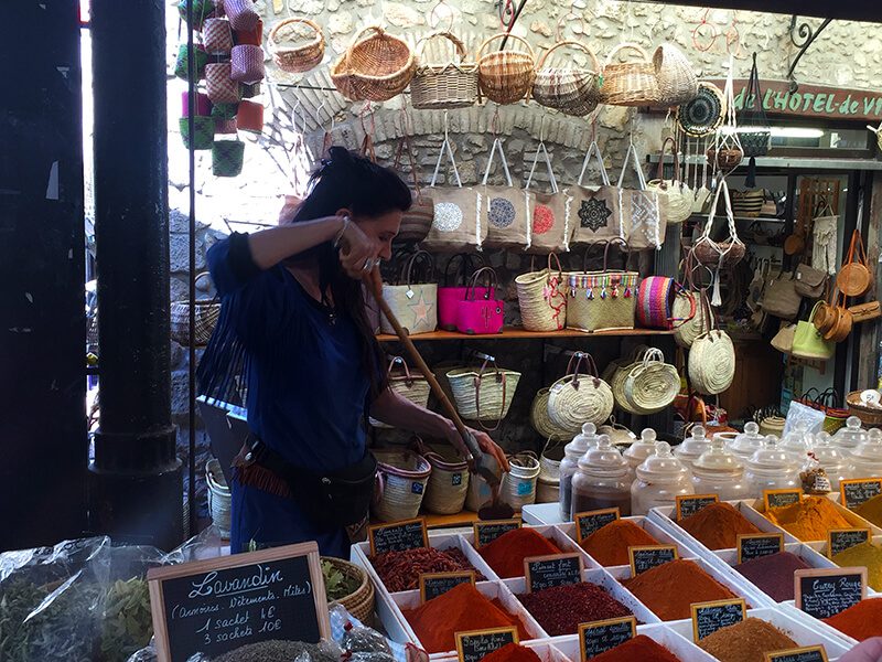 A woman is standing in front of a display of spices.