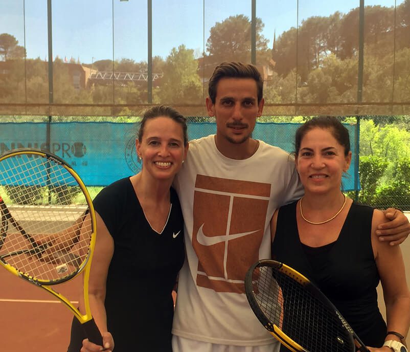 Three tennis players posing for a picture on the court