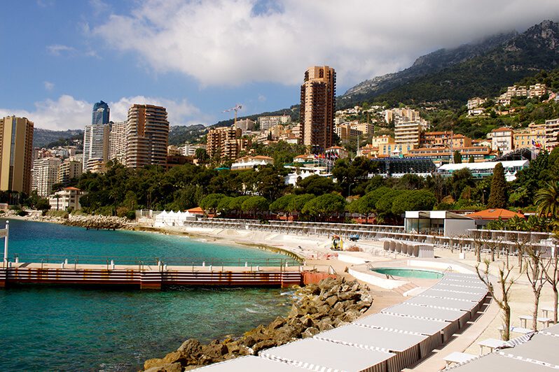 A beach with many white umbrellas and some buildings