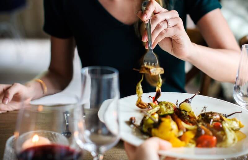 A person eating food on top of a white plate.