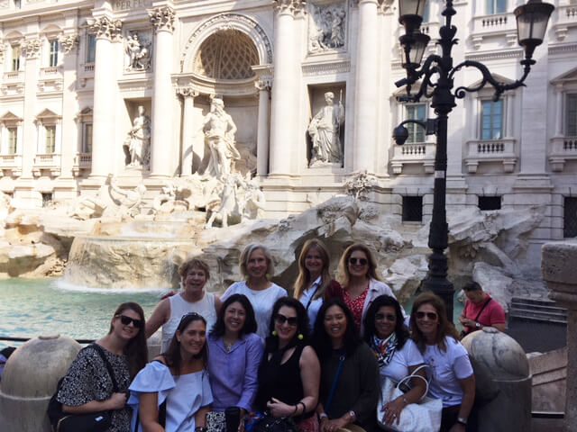 A group of women standing in front of the trevi fountain.