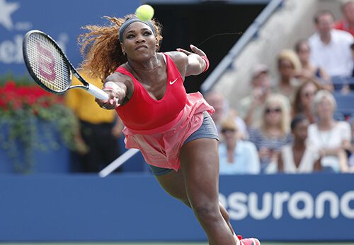 A woman swinging at a tennis ball with her racket.