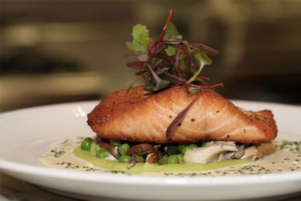 A piece of fish is on top of some vegetables.