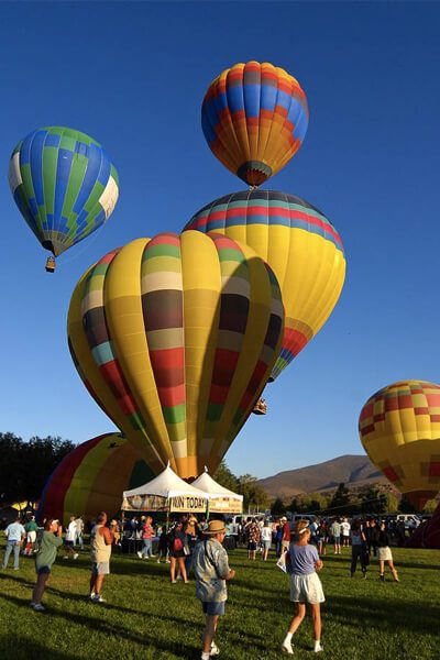 A group of people standing around a field with balloons.