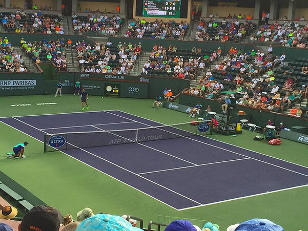 A tennis court with people watching it.