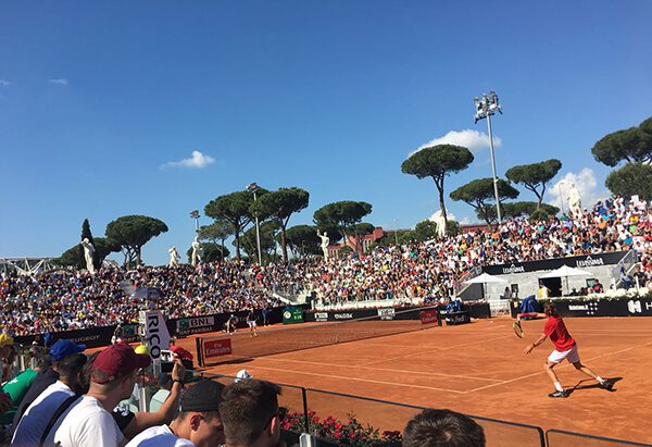 A crowd of people watching tennis players play.