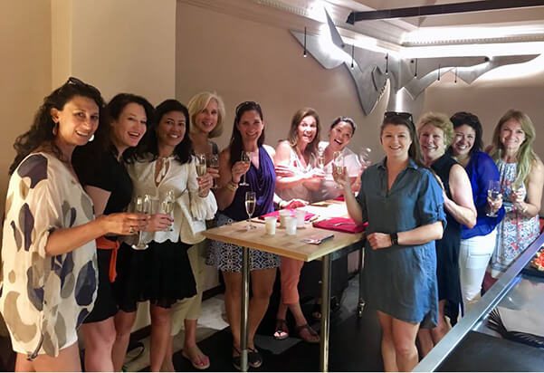 A group of women holding wine glasses and posing for the camera.