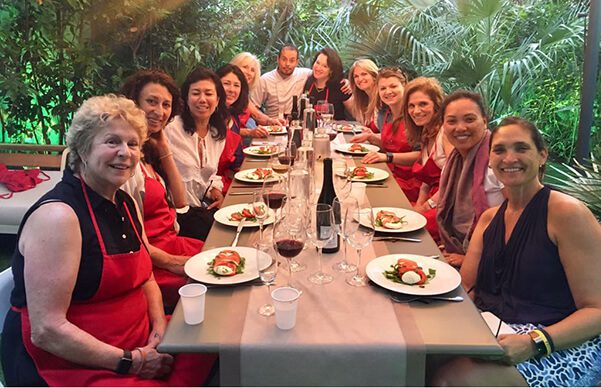 A group of people sitting at the table with plates and wine.