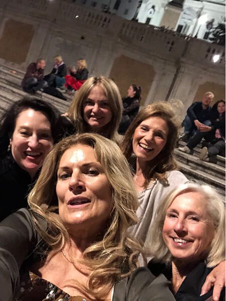A group of women taking a selfie in front of some people.