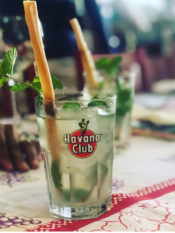 A glass of mojito with straws in it.