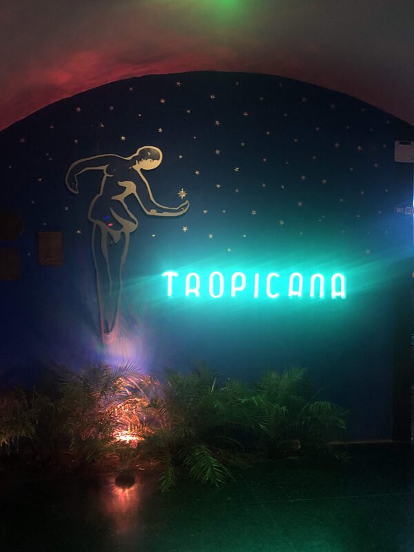 A neon sign that says tropicana in front of a wall.